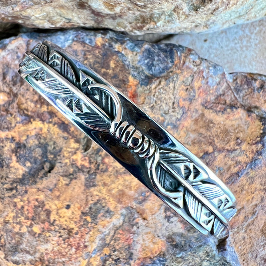 Silver feather design on a stone background