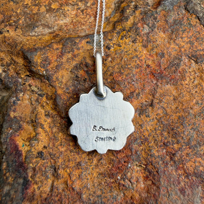 Back of silver pendant necklace on a textured stone background