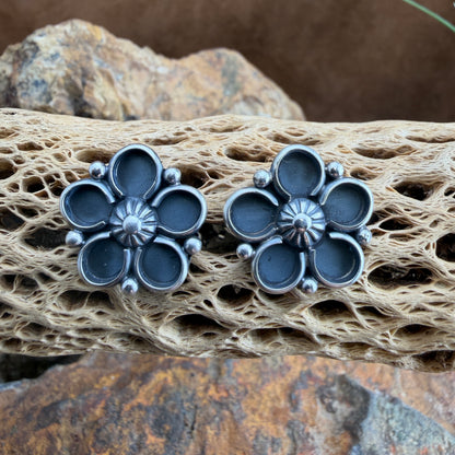 Pair of silver flower-shaped earrings on a textured stone surface