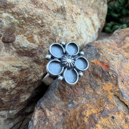 Silver flower-shaped ring on a textured stone surface