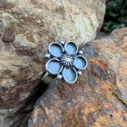 Silver flower-shaped ring on a textured stone surface