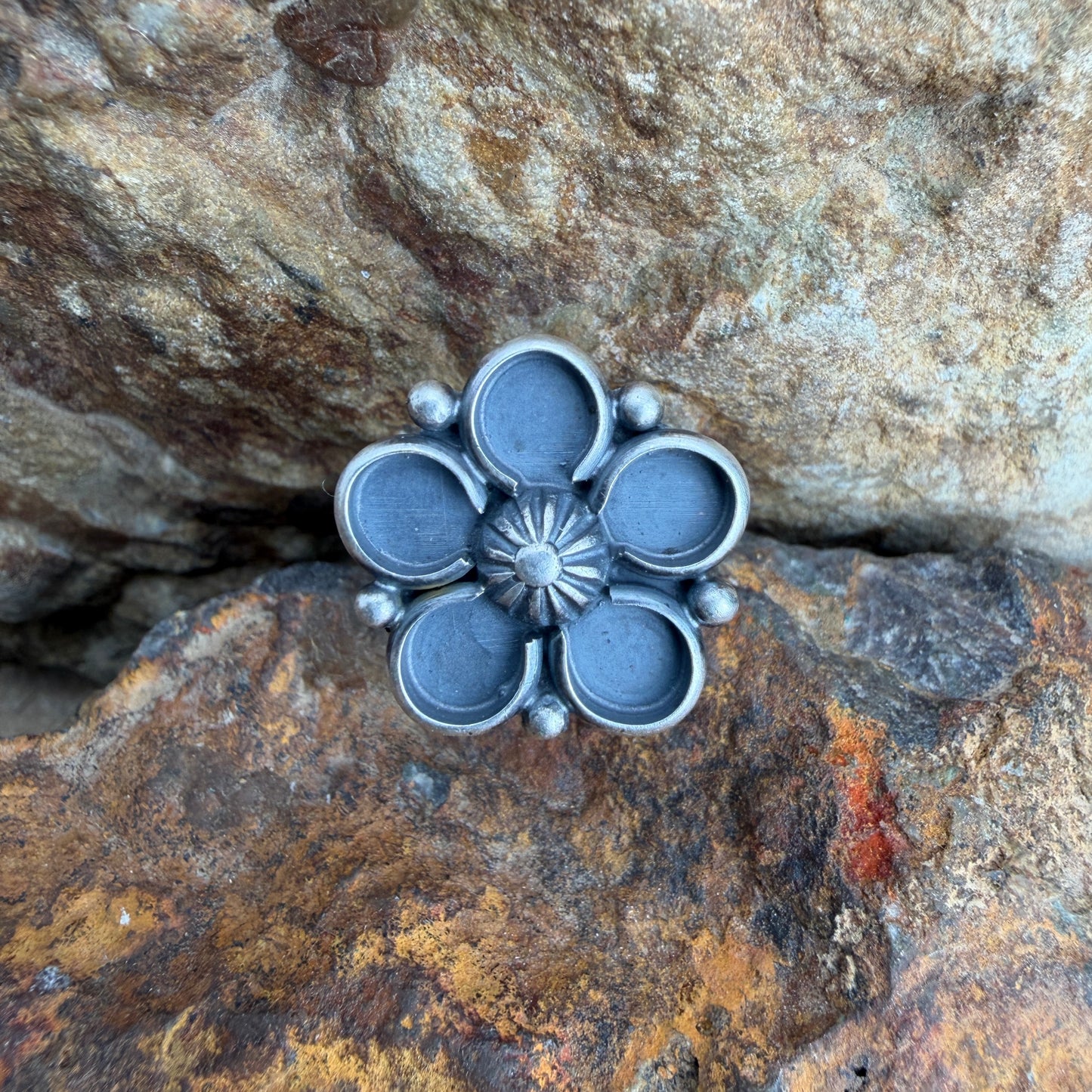 Silver flower-shaped object on a textured stone surface