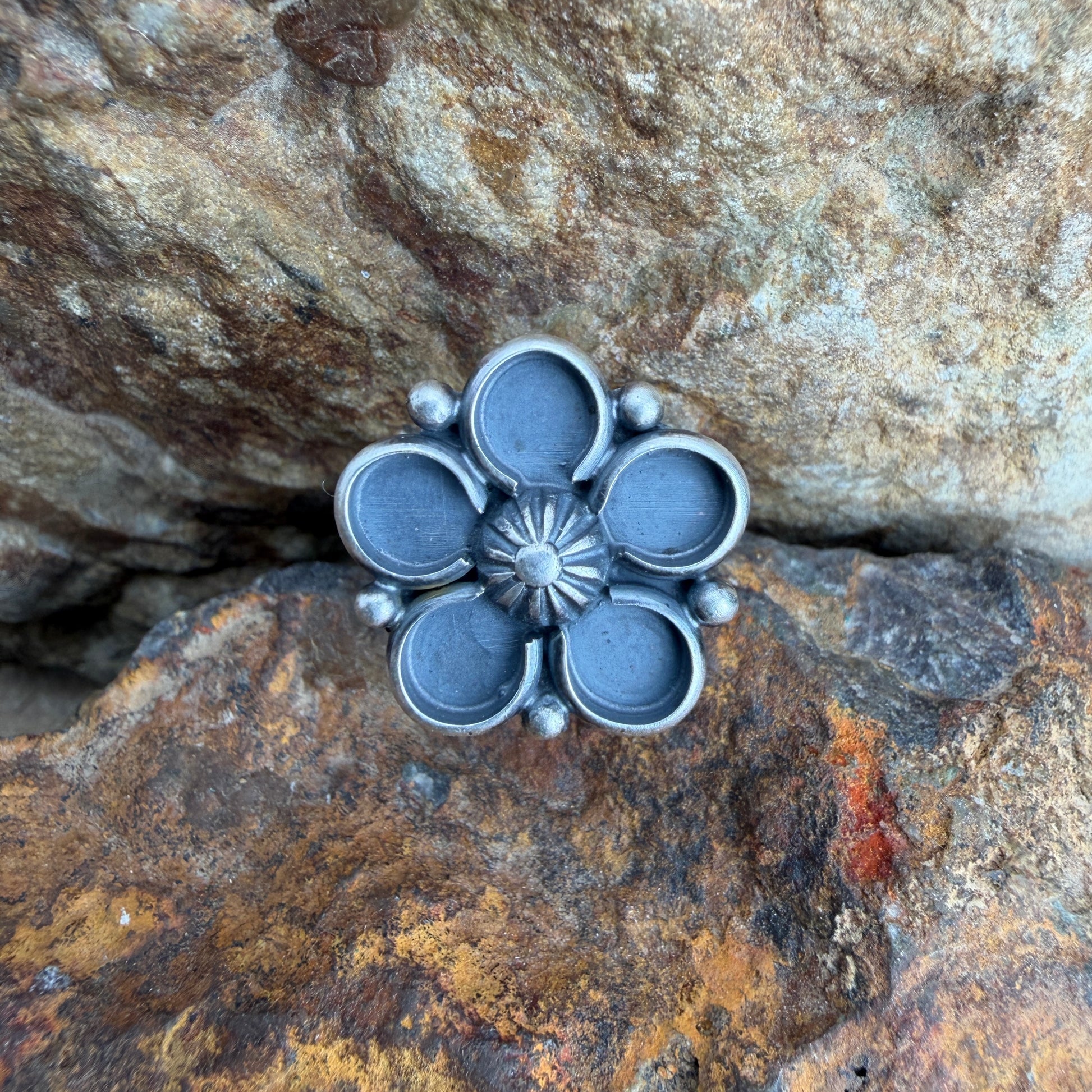 Silver flower-shaped object on a textured stone surface