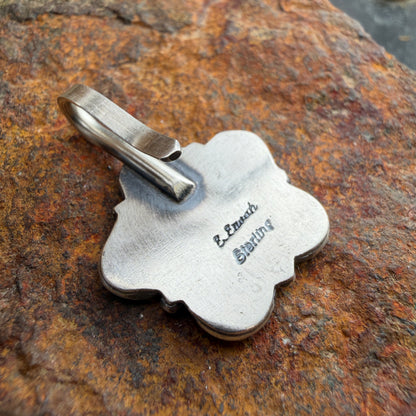 Silver pendant with engraved text "E. Enoah" on a textured stone surface