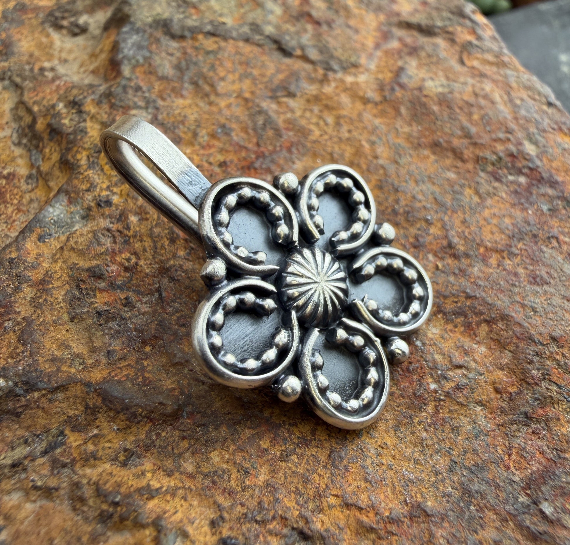 Silver floral pendant on a textured stone background