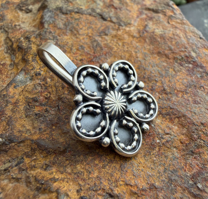 Silver floral pendant on a textured stone background