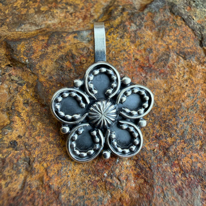 Silver floral pendant on a textured stone background