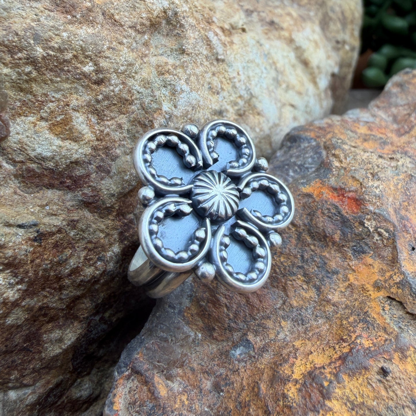 Silver floral ring on a textured stone surface