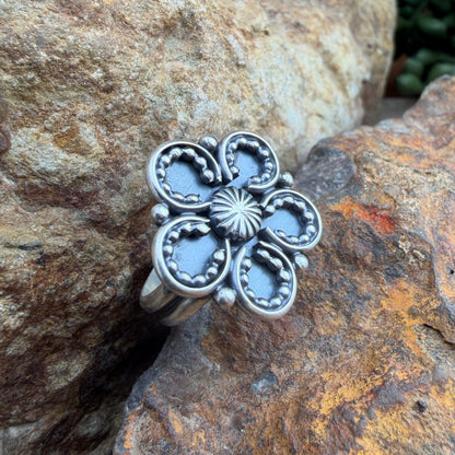 Silver floral ring on a textured stone surface