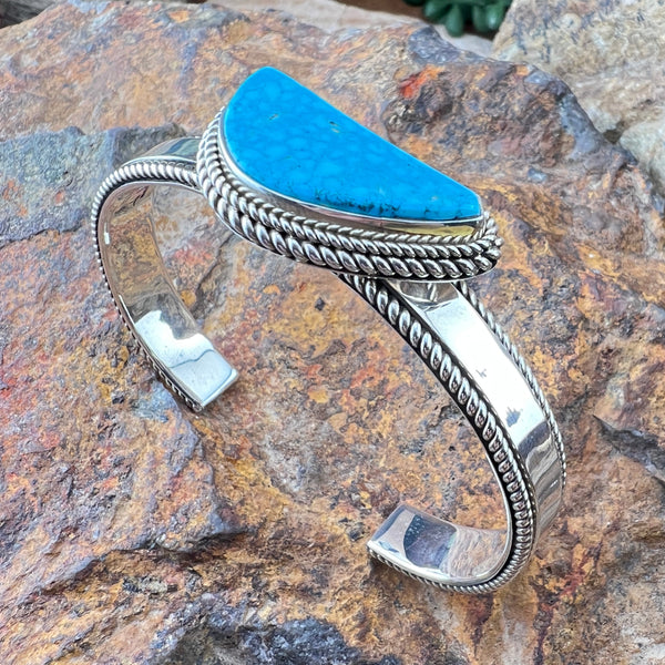 Silver bracelet with a turquoise stone on a stone surface