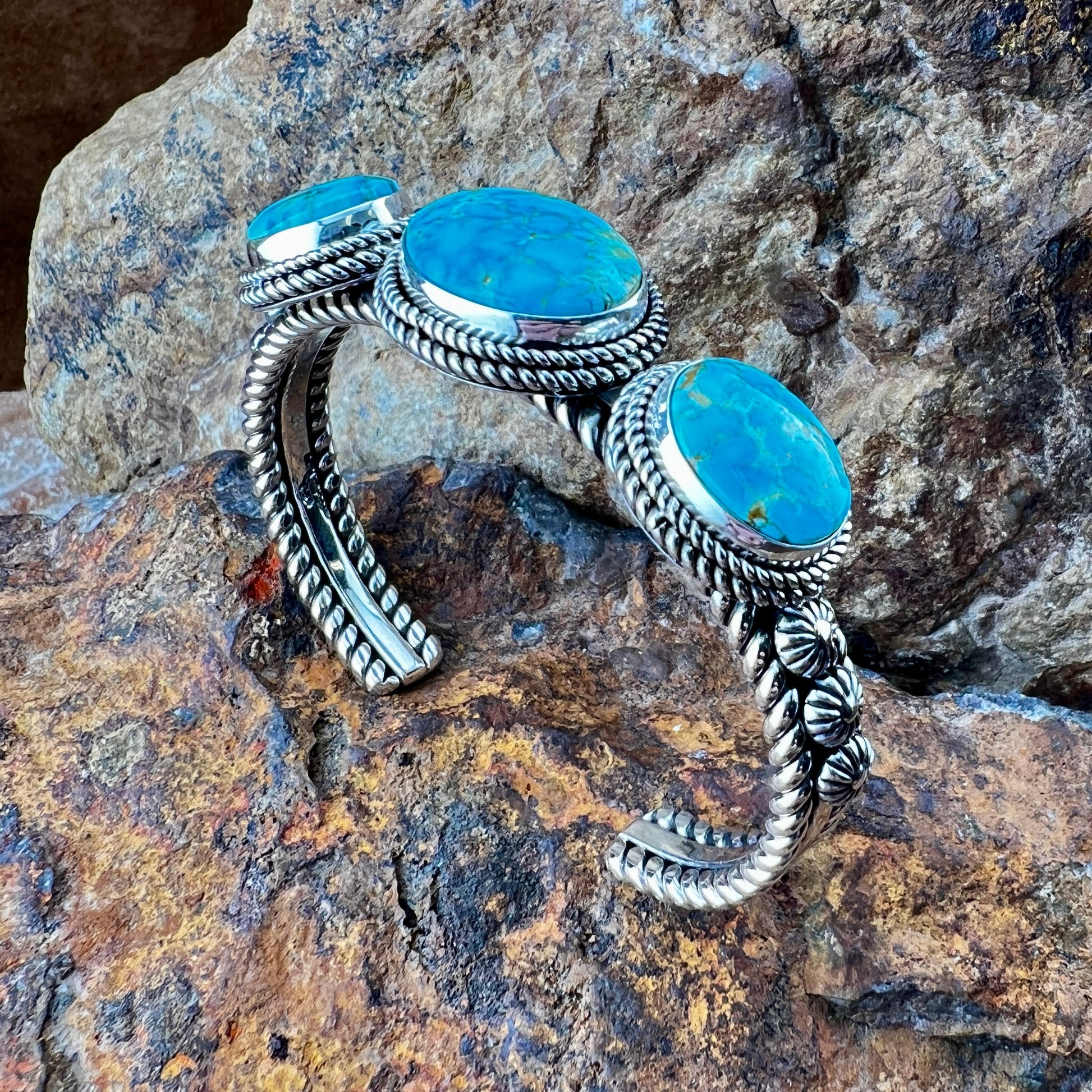 Silver bracelet with turquoise stones on a rocky surface
