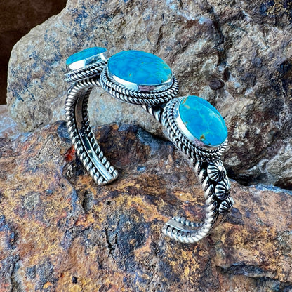 Silver bracelet with turquoise stones on a rocky surface