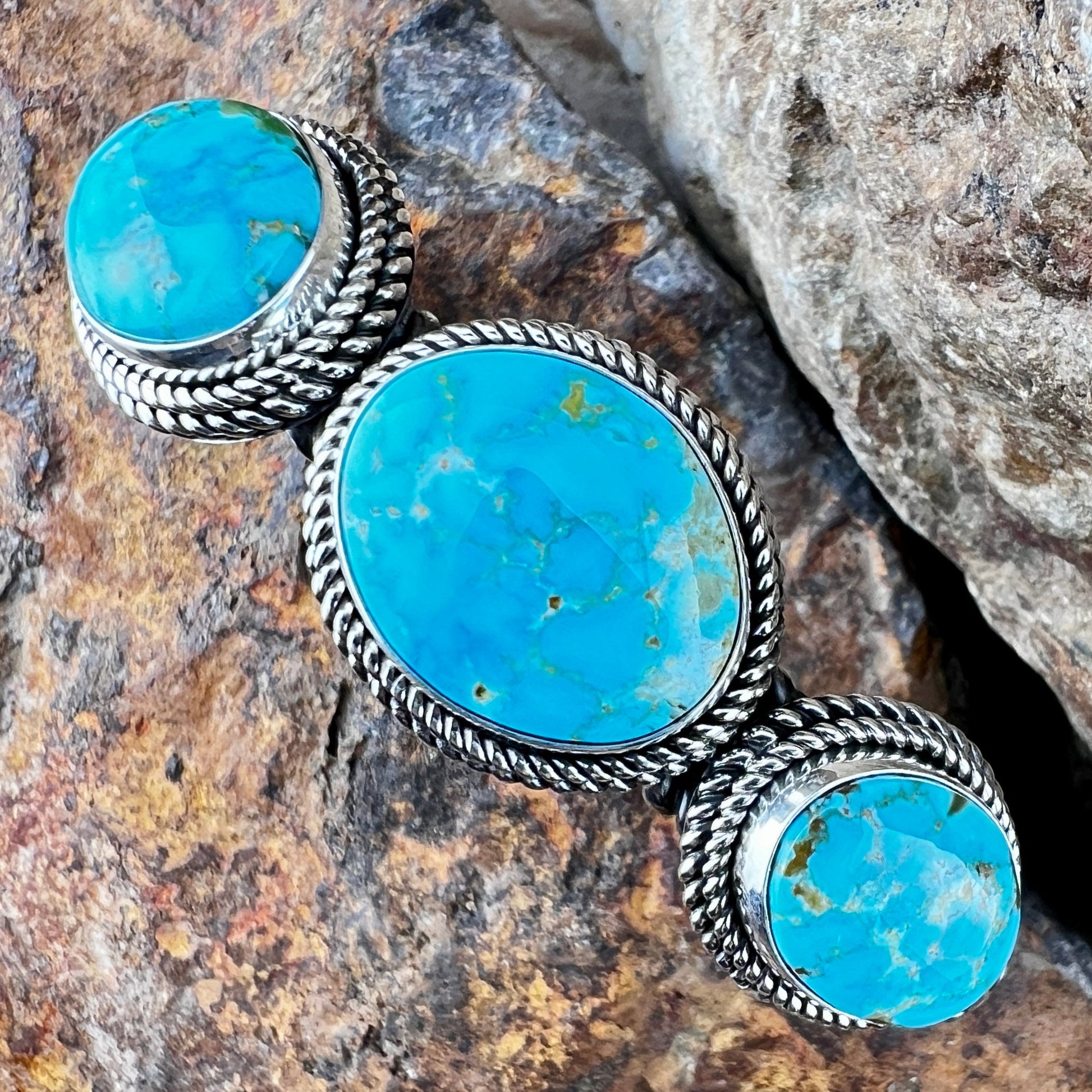 Turquoise stone bracelet with silver band on a rocky surface