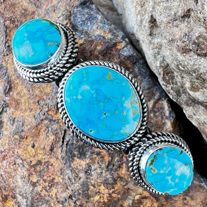 Turquoise stone bracelet with silver band on a rocky surface