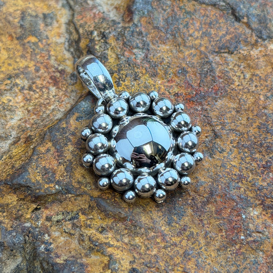 Sterling Silver Hematite Million Drop Pendant by Artie Yellowhorse - front view on rock showing faceted hematite center with double row silver sphere halo