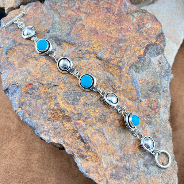 Silver bracelet with blue stones on a textured stone surface