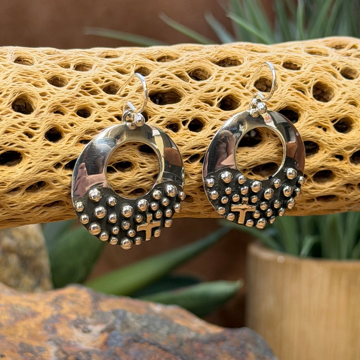 Open-circle silver earrings showing raised beads and cross accents