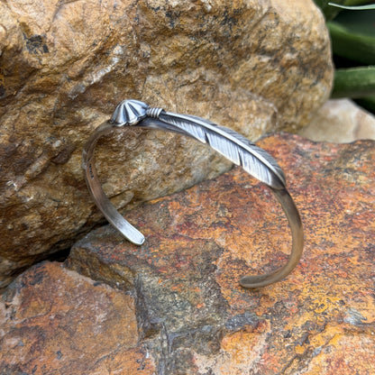 Angled view of Ray Coriz sterling silver feather and floral concho cuff with open band