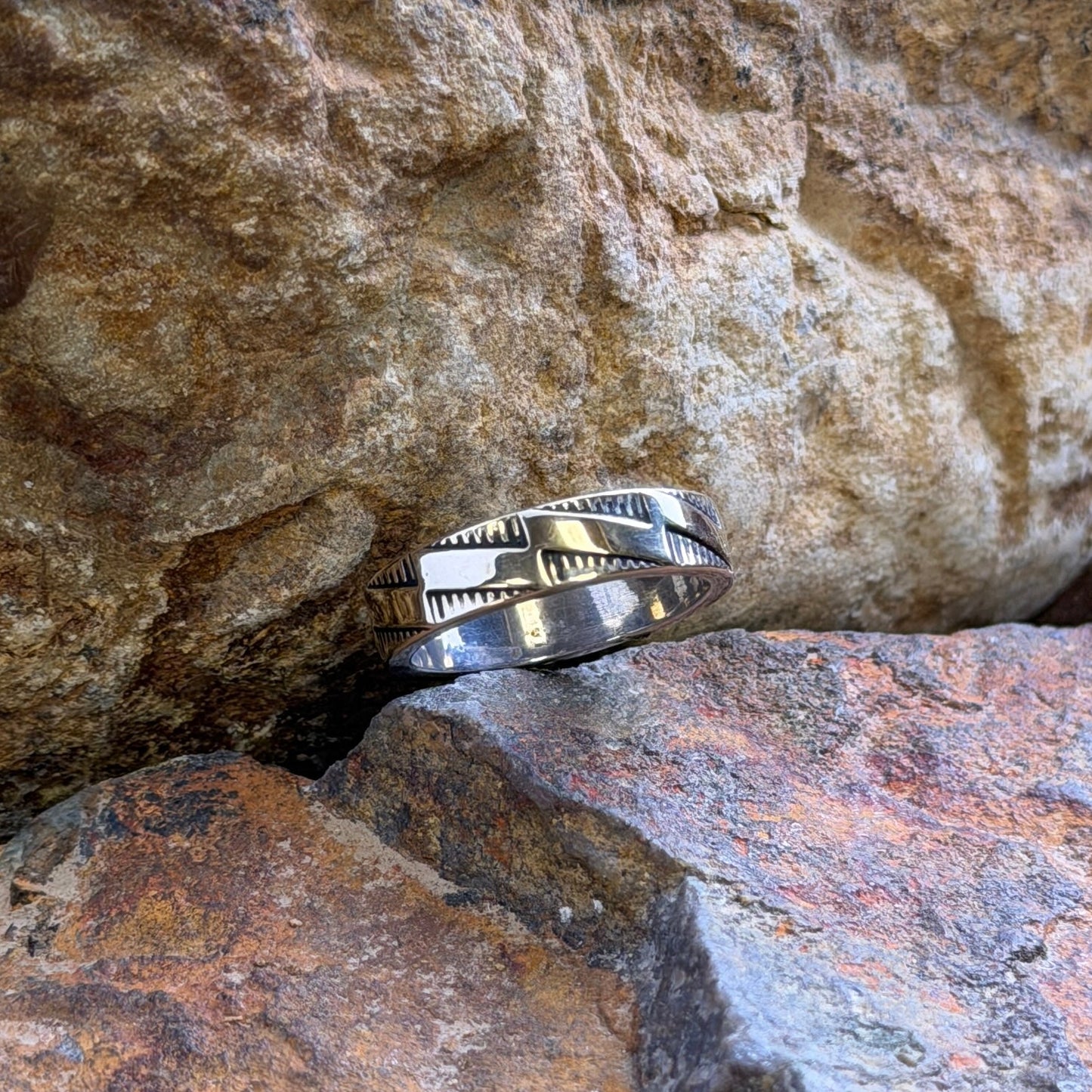 A silver band ring with stepping geometric patterns
