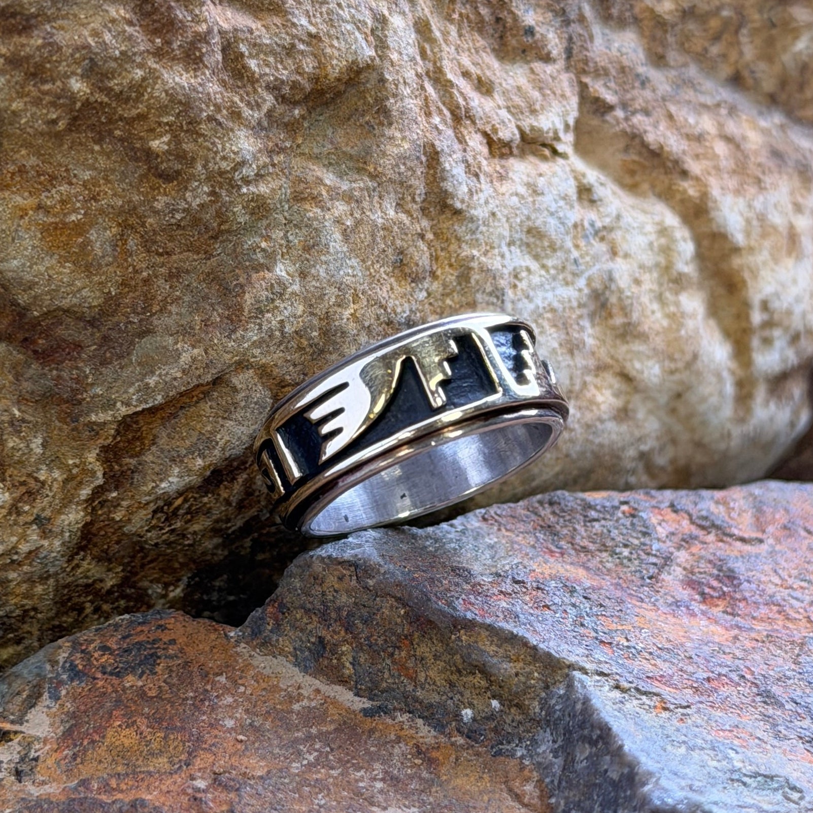a gold overlayed ring resting on textured brown and gray rocks.