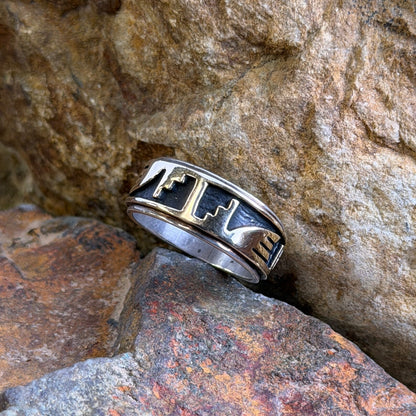 A gold overlayed ring on a black background with geometric patterns
