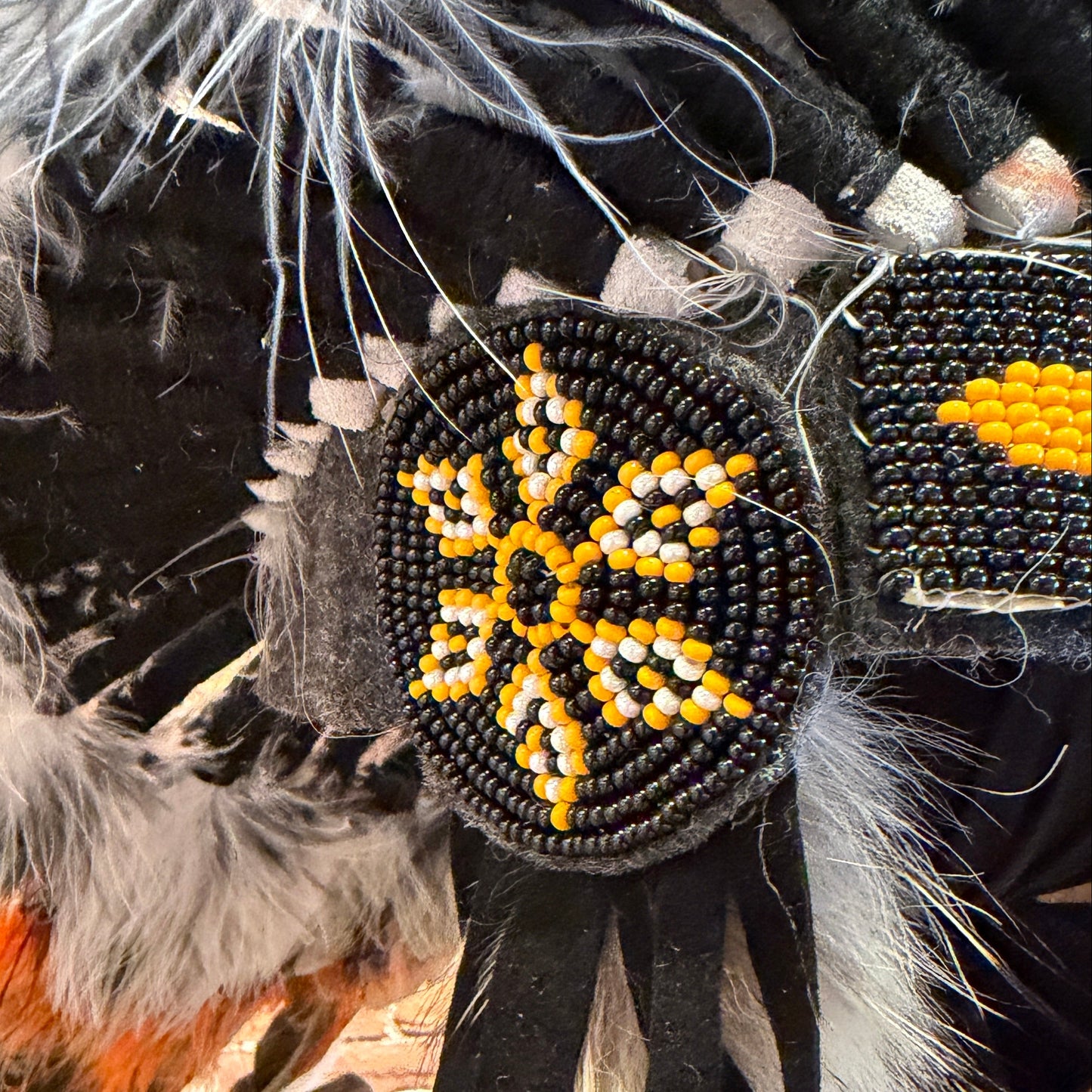 Decorative item with beads and feathers against a brick wall background