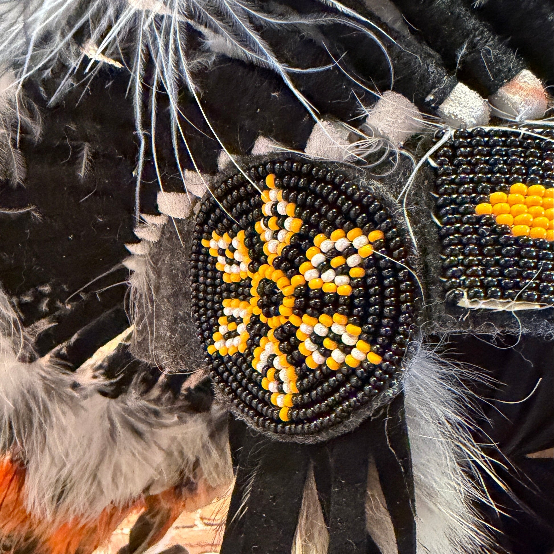 Decorative item with beads and feathers against a brick wall background