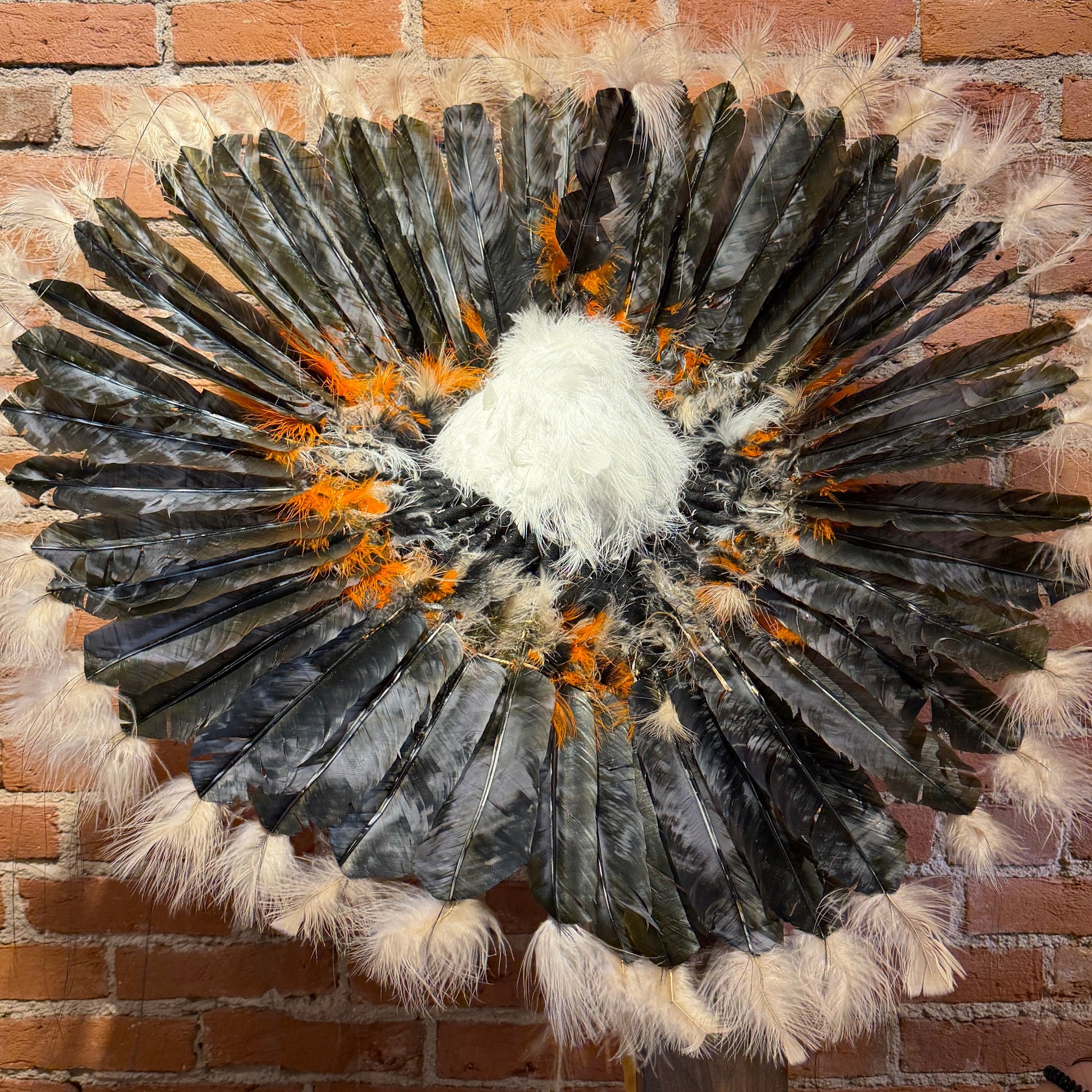 Feathered wall art piece against a brick wall