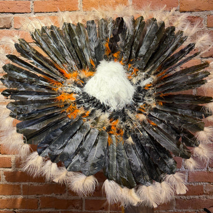 Feathered wall art piece against a brick wall