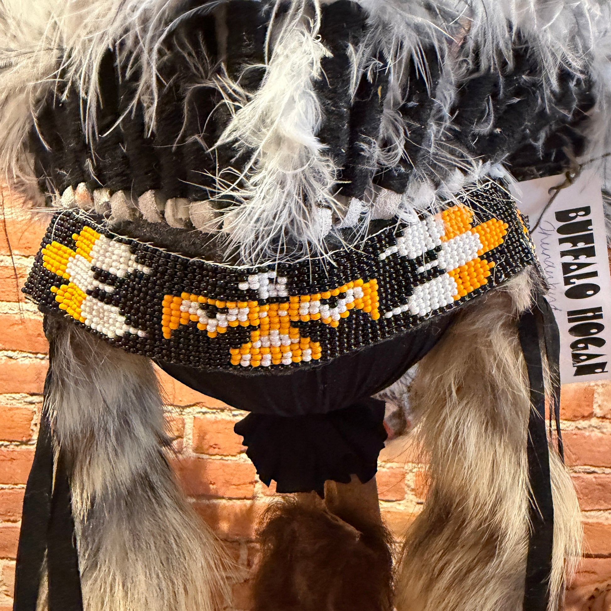  a headdress with beadwork and feathers against a brick wall.