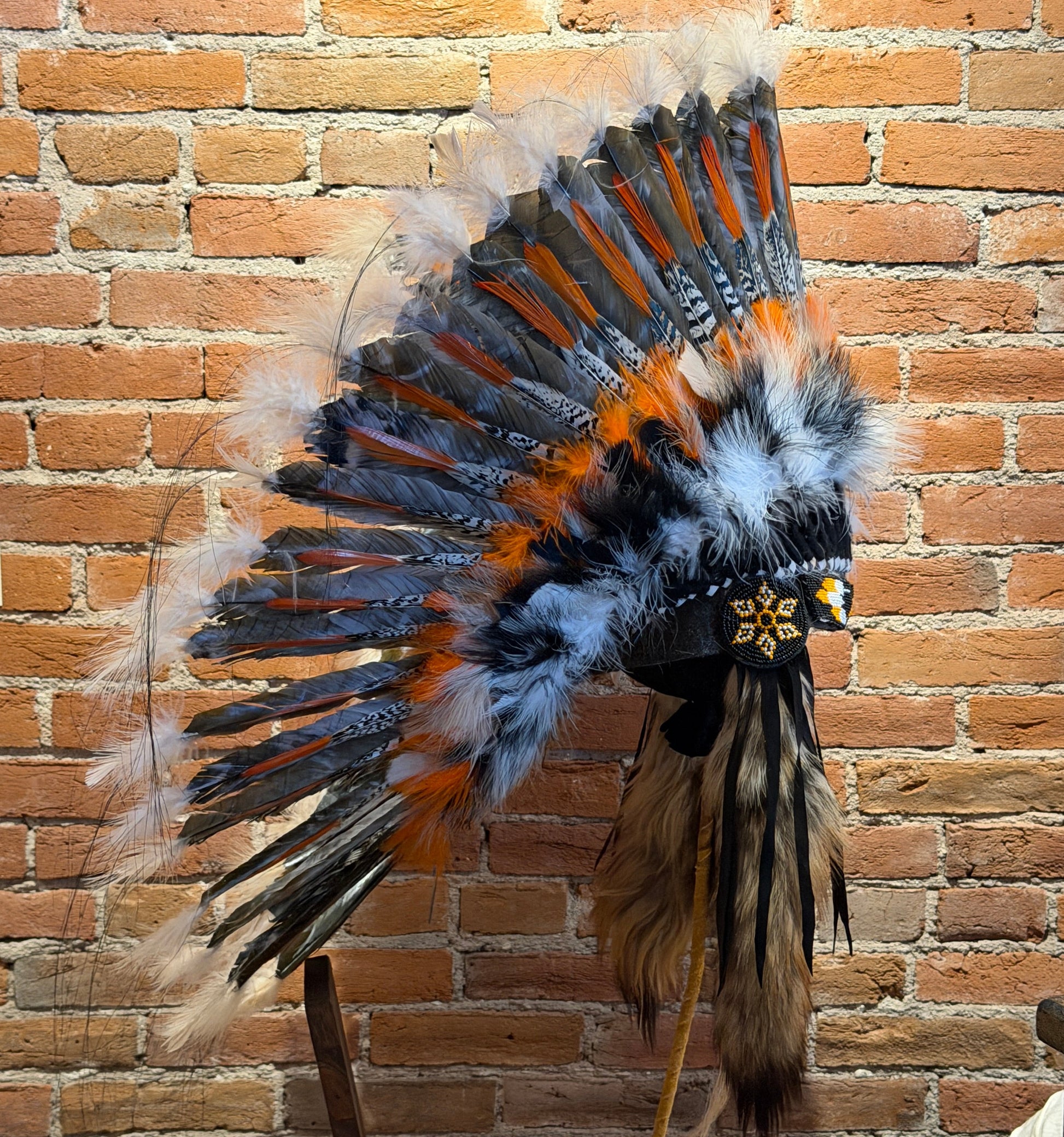 Feather headdress against a brick wall