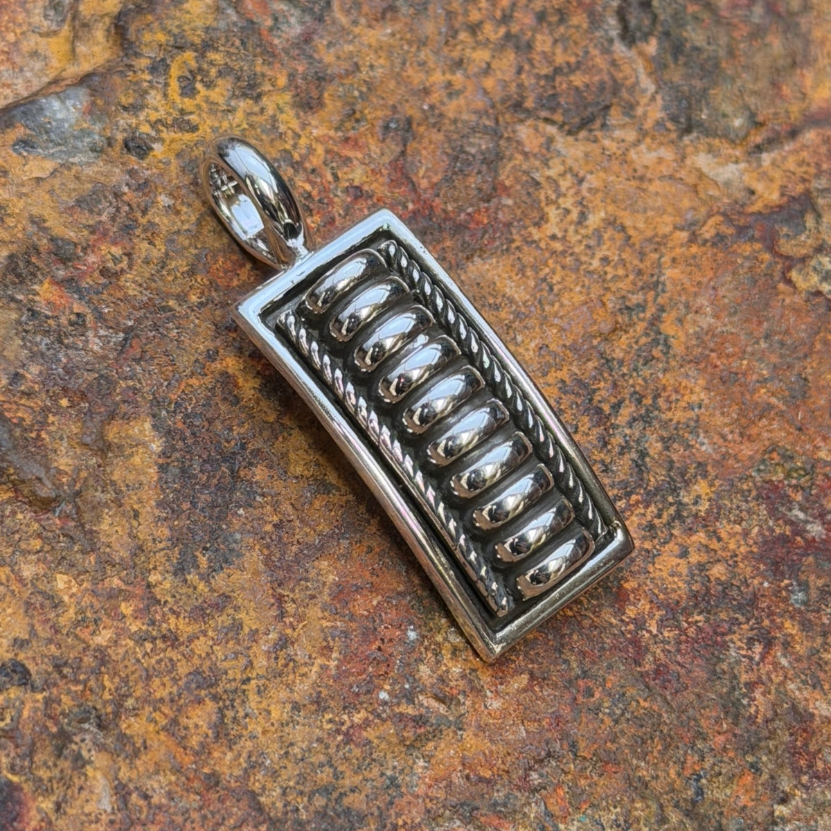 Front of Tom Charlie rectangular sterling silver pendant with raised silver bars