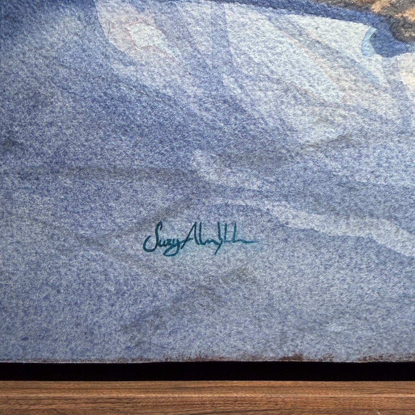 Textured blue surface with a signature and wooden base