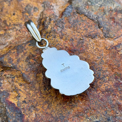 royal lapis pendant in the shape of an arrowhead decorated by silverwork by mary tso. displays the hallmark side