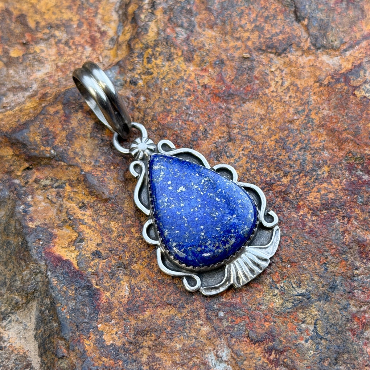 royal lapis pendant in the shape of an arrowhead decorated by silverwork by mary tso