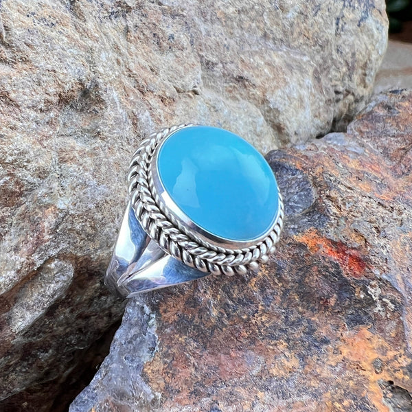Silver ring with a blue stone on a rocky surface