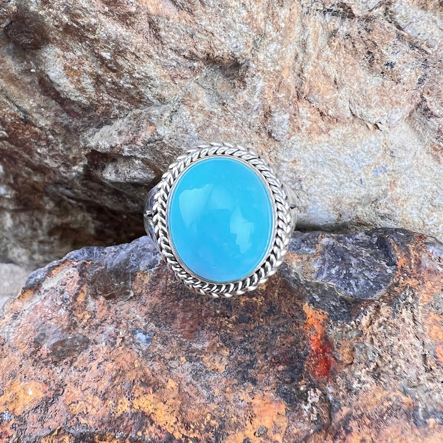 Turquoise ring with silver band on a rocky surface