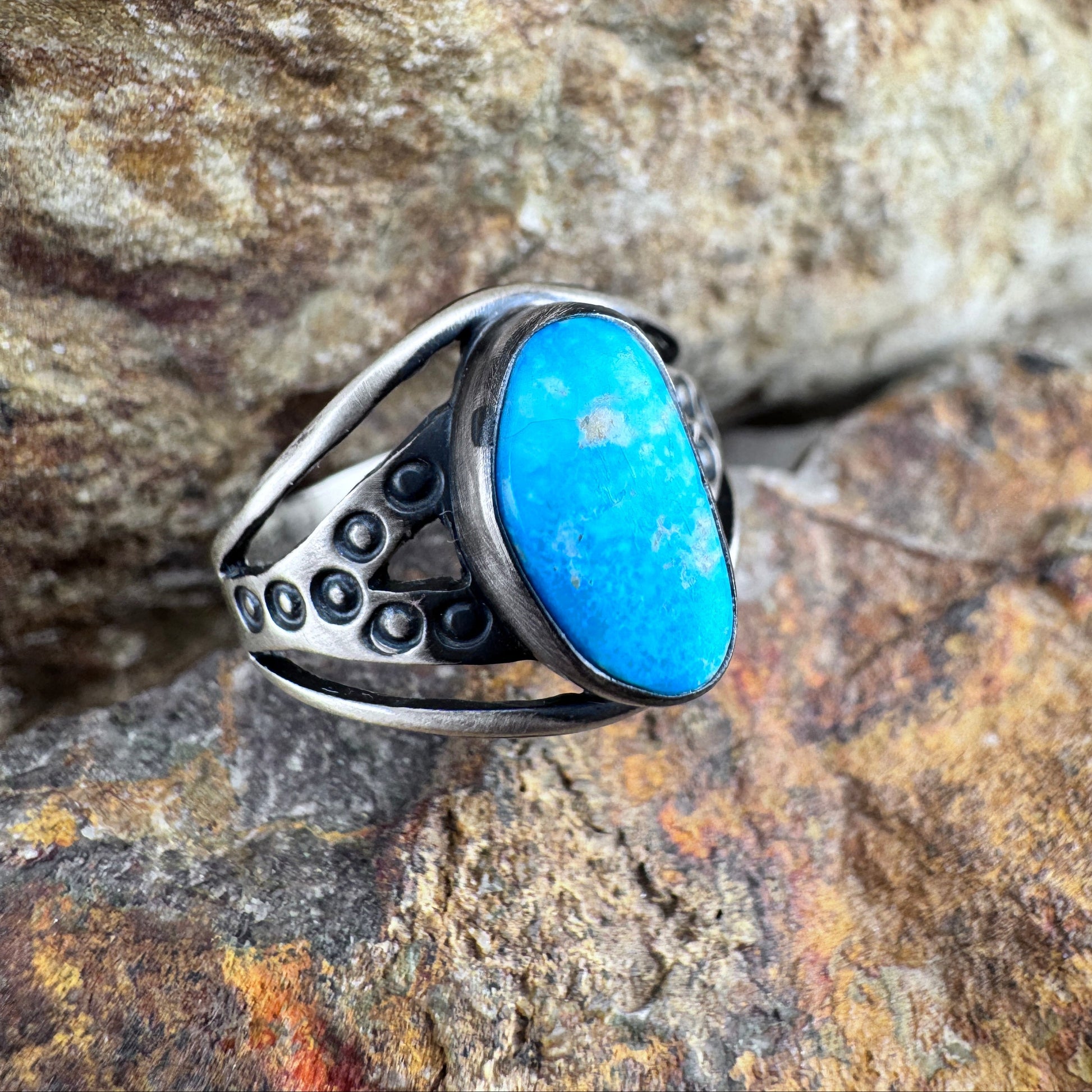 Silver ring with a blue stone on a rocky background