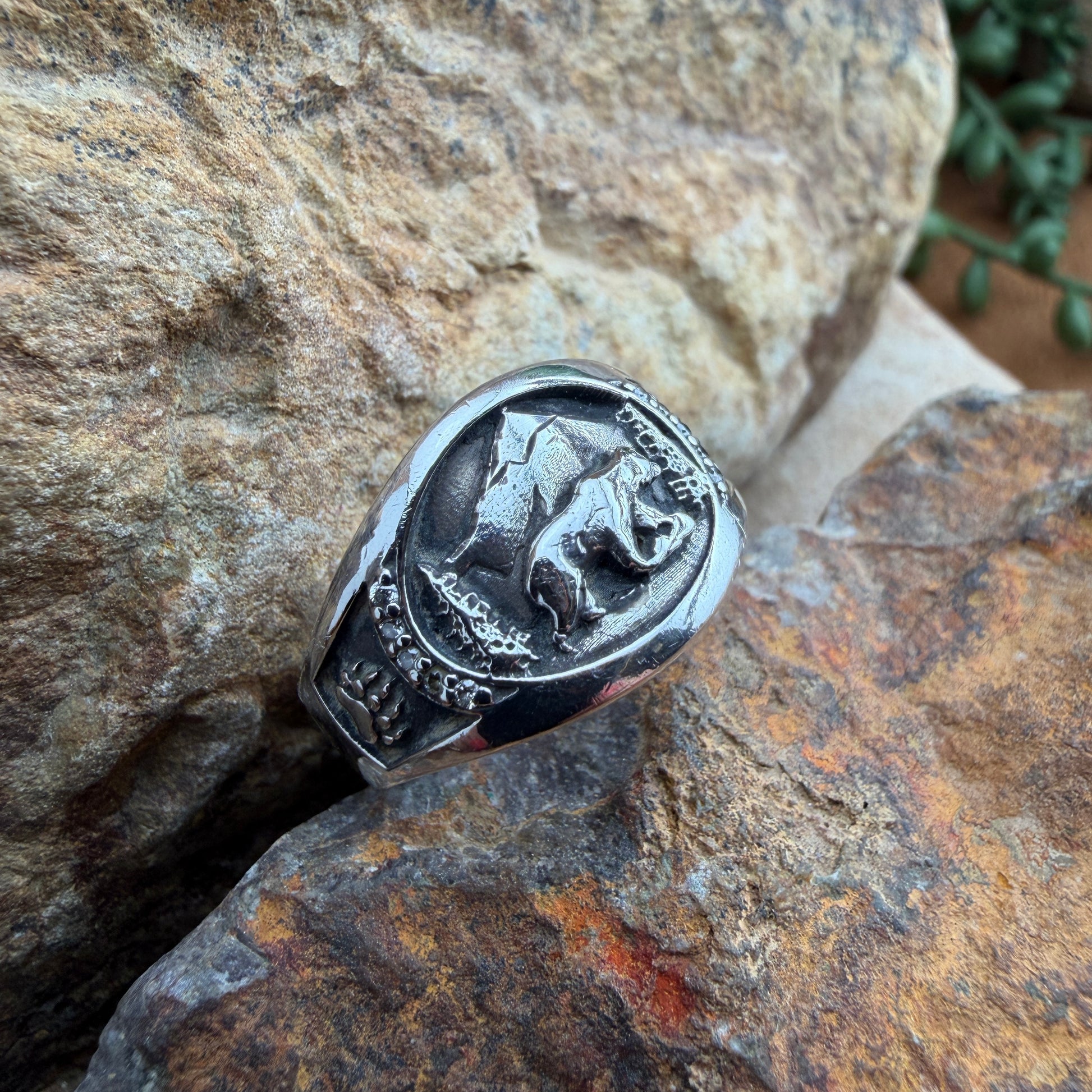 Image of a sterling silver ring with a bear engraving amongst natural scenery 