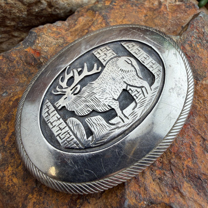 Silver belt buckle with deer design on a stone background