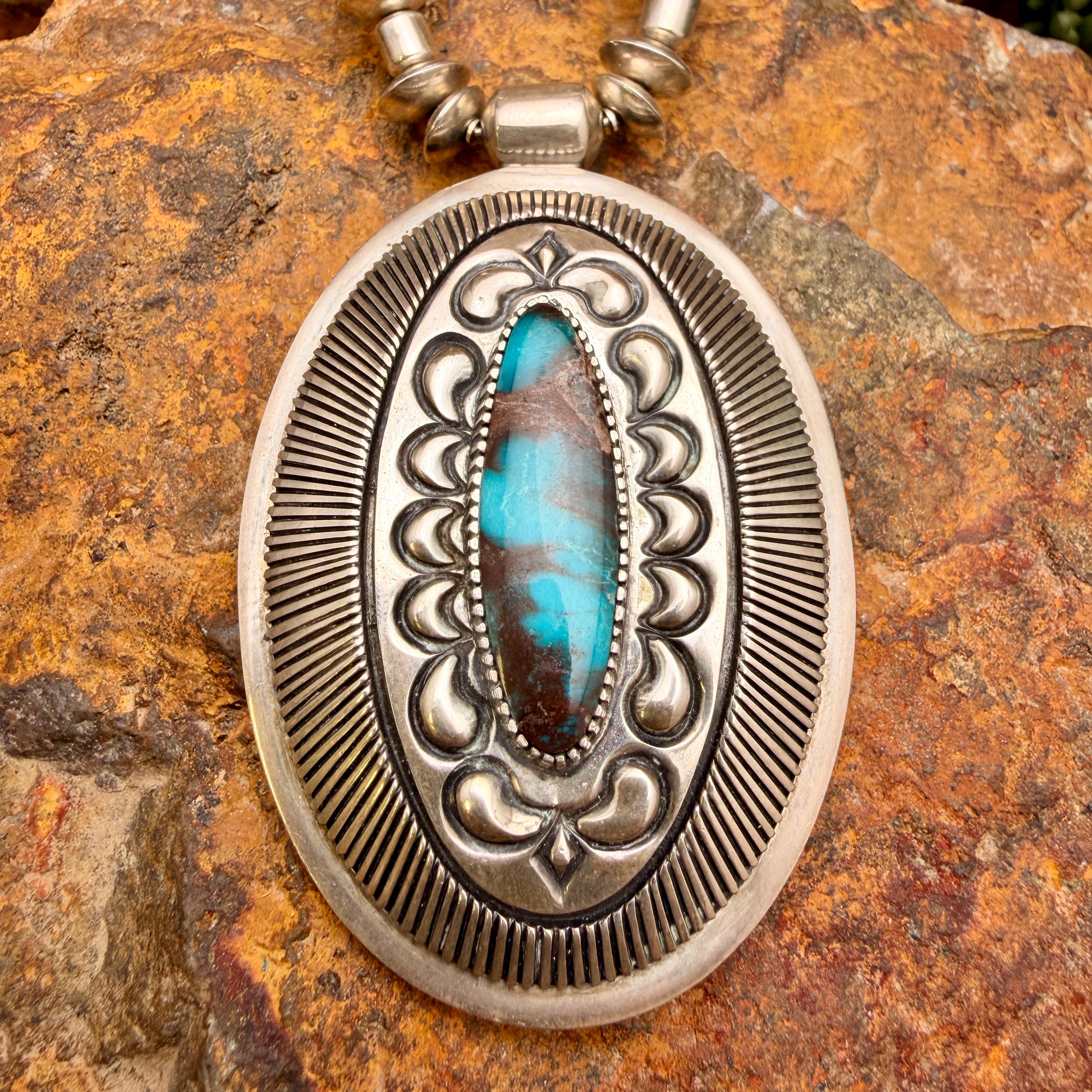 large pendant with turquoise centerpiece surrounded by stamp work