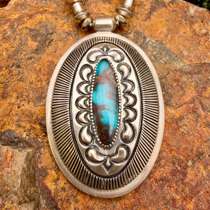 large pendant with turquoise centerpiece surrounded by stamp work