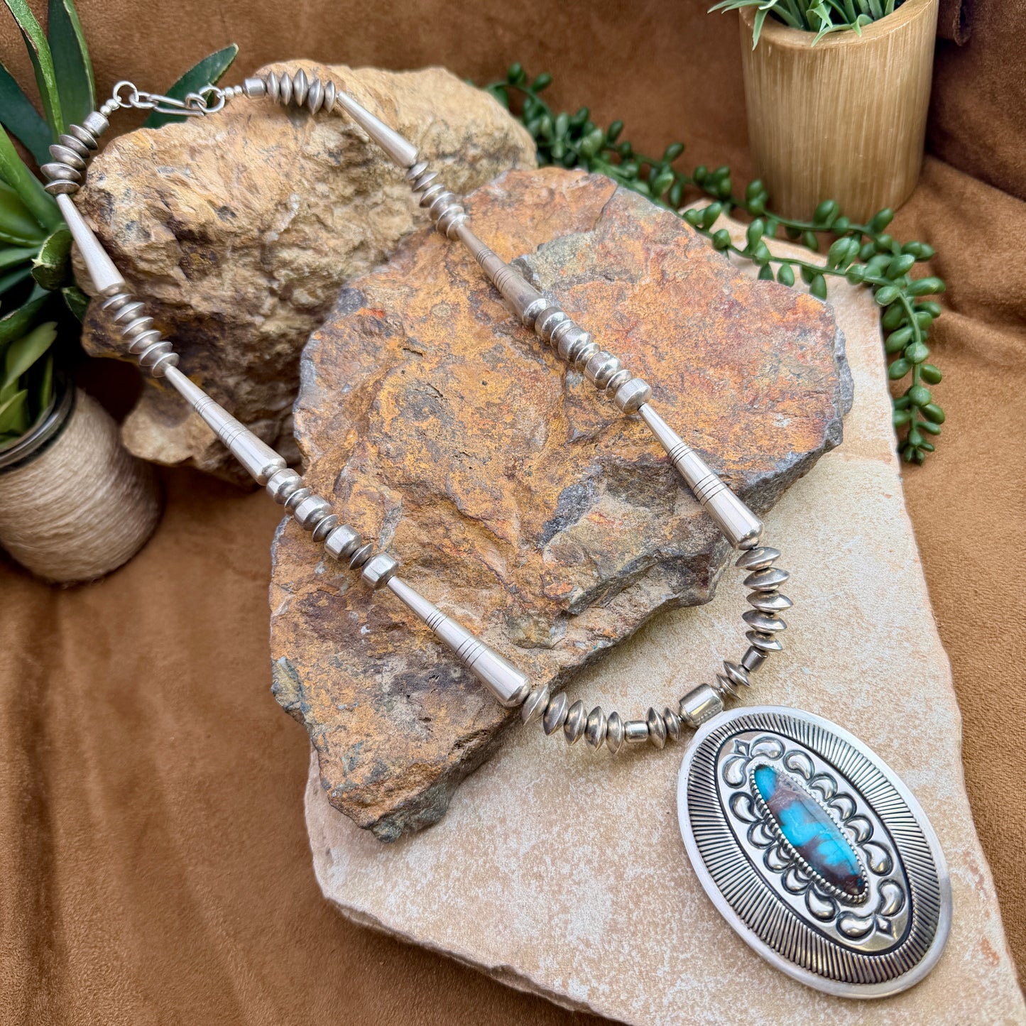 Navajo pearl necklace with an array of torpedo beads, saucers, and a large center pendant that encases turquoise.