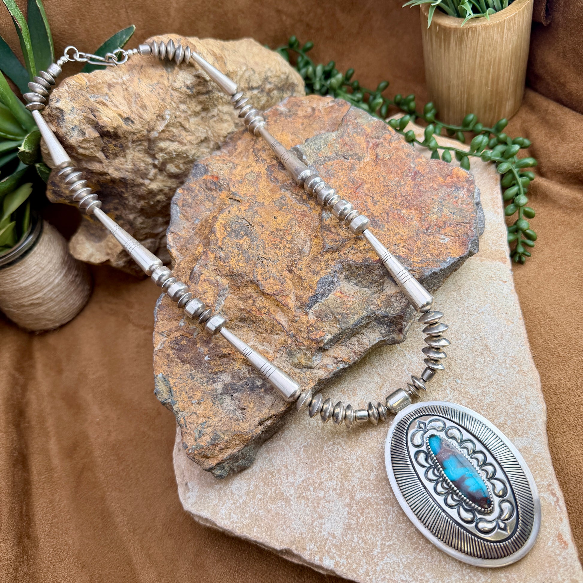 Navajo pearl necklace with an array of torpedo beads, saucers, and a large center pendant that encases turquoise.