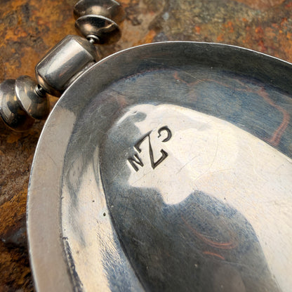 Close-up of a silver pendant with engraved initials  GZN on a textured surface