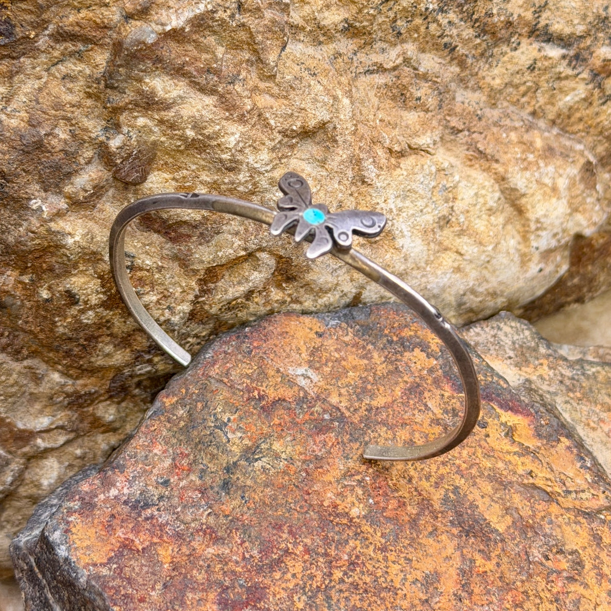 Close-up of stamped butterfly wings and blue turquoise center on vintage silver cuff