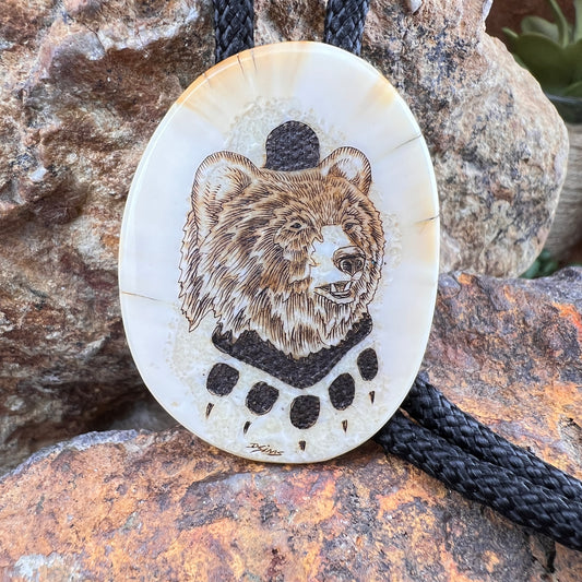 Round pendant with bear design on a stone surface