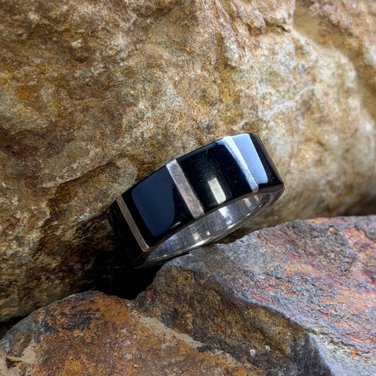 A black and silver striped ring resting on textured brown and orange rocks.