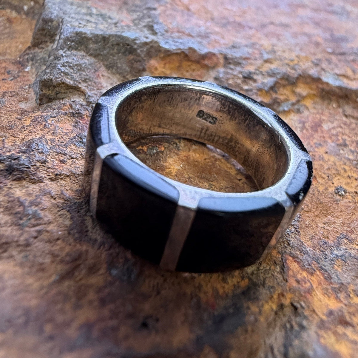 The inside of a ring that displays .925 stamp. it is resting on a stone surface. 