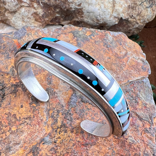Silver bracelet with colorful inlay on a stone surface